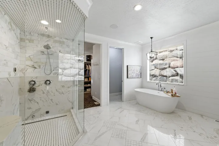 Bathroom with a freestanding tub, a marble finish shower, a textured ceiling, light marble finish floors, and recessed lighting