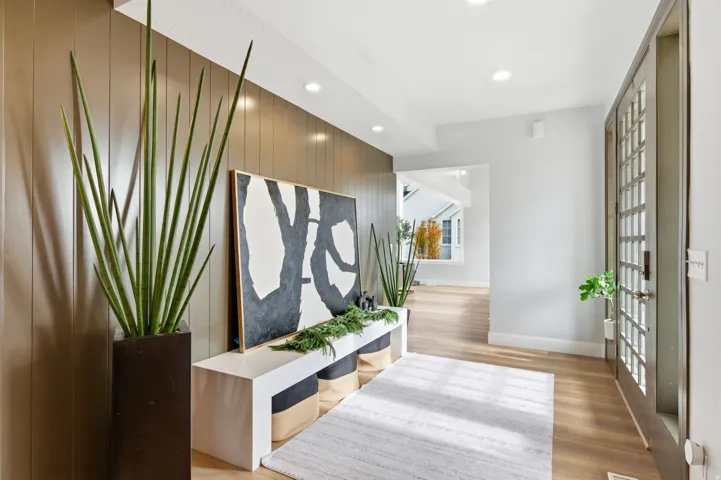 Corridor with an accent wall, recessed lighting, light wood-style flooring, and wood walls