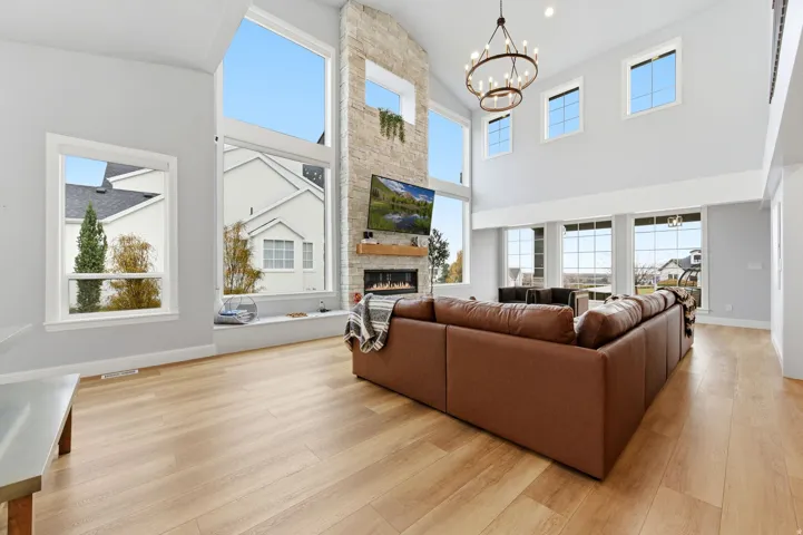 Living room with a fireplace, light wood finished floors, a chandelier, and plenty of natural light