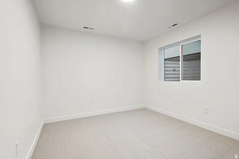Spare room with light carpet and baseboards