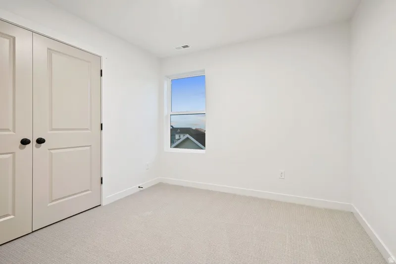Unfurnished bedroom featuring light carpet and a closet