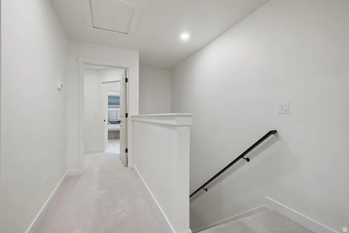 Hall with an upstairs landing, light carpet, and recessed lighting