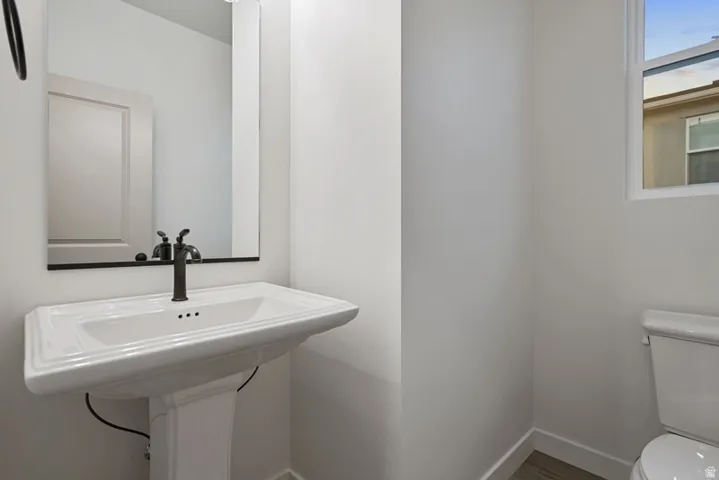Half bath featuring toilet and wood finished floors