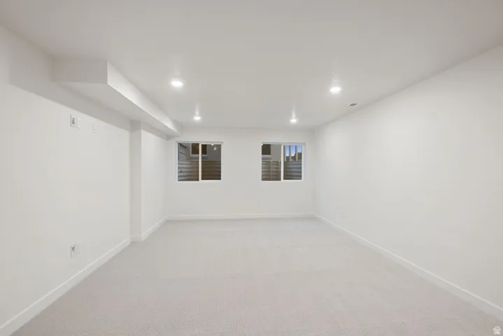 Finished below grade area featuring light colored carpet and recessed lighting