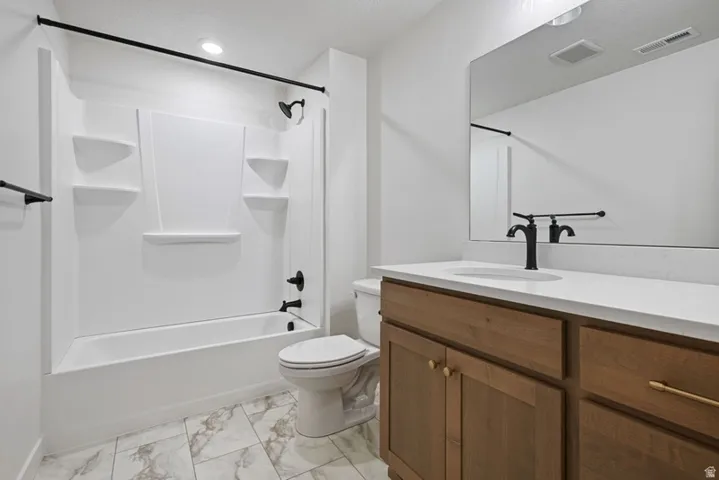 Bathroom with vanity, tub / shower combination, and light marble finish flooring