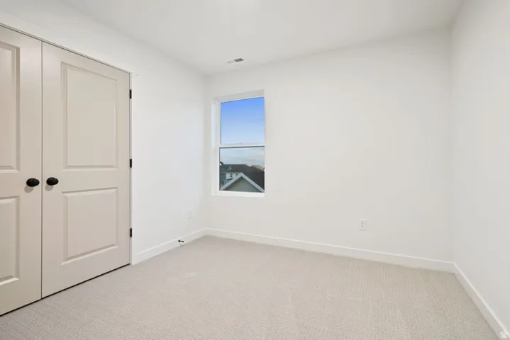 Unfurnished bedroom featuring light carpet and a closet