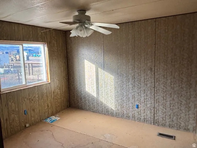 Unfurnished room with wooden walls and ceiling fan