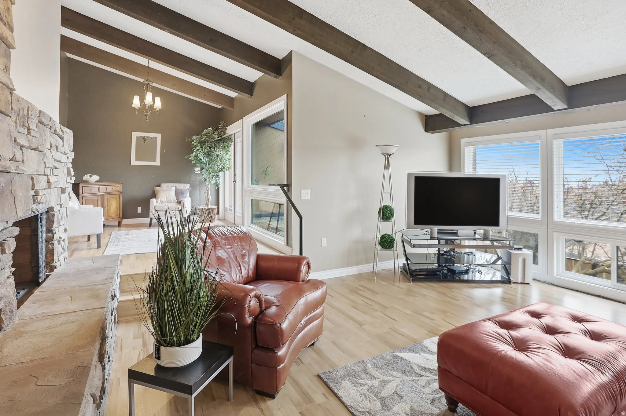 Living room with a fireplace, a chandelier, wood finished floors, and healthy amount of natural light