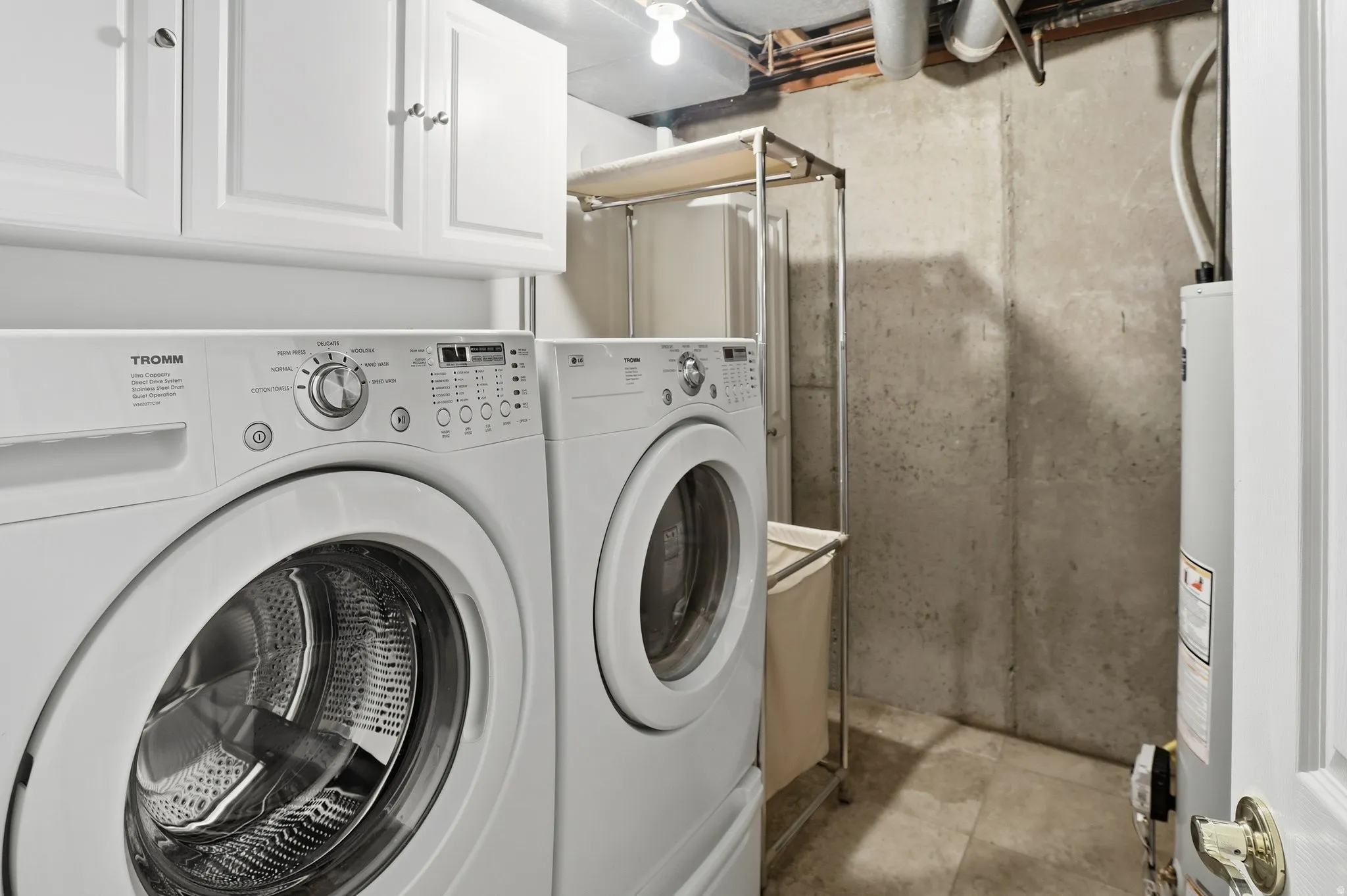 Washroom with cabinet space, water heater, and washer and clothes dryer