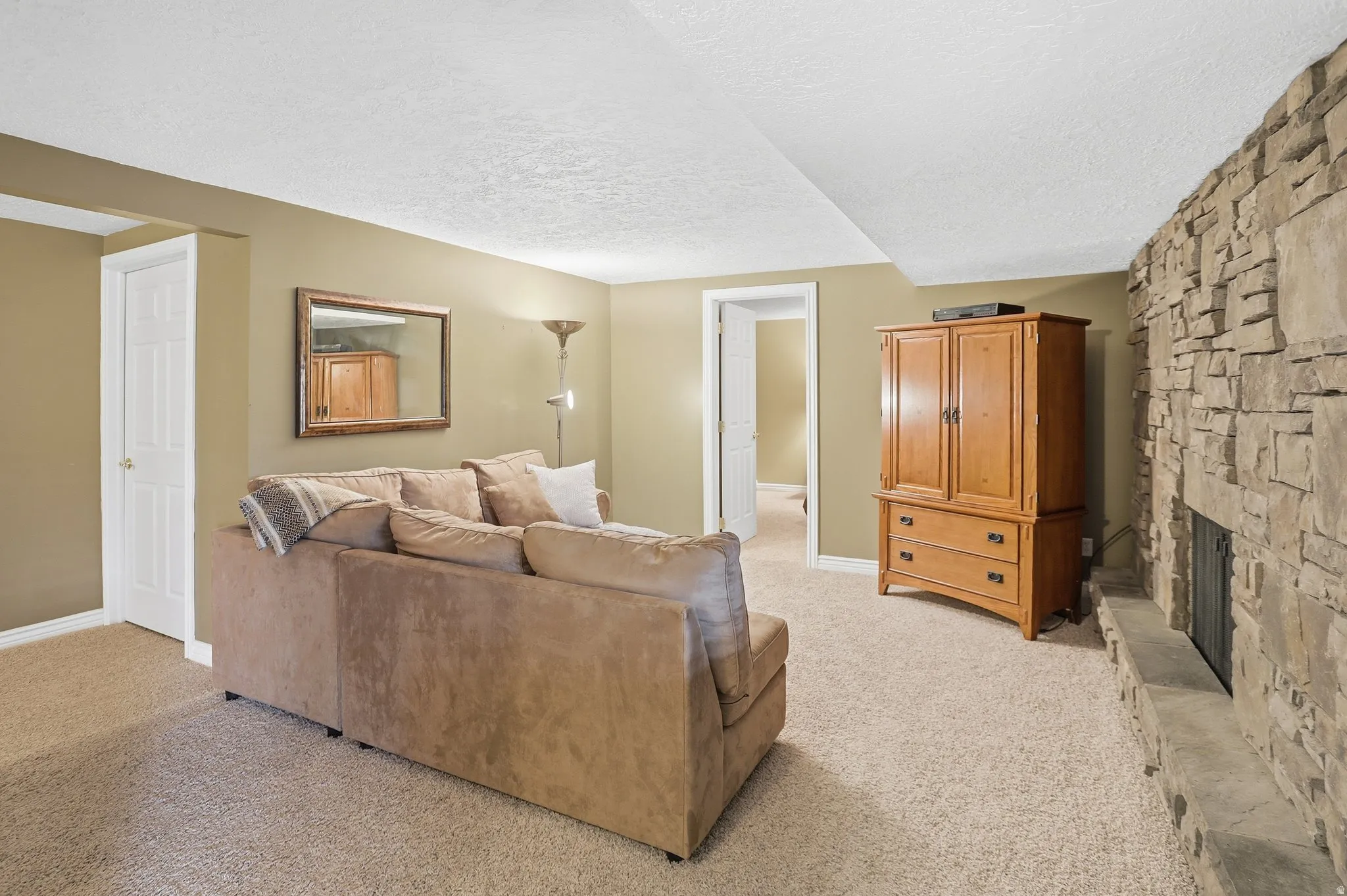 Living area with a textured ceiling, light carpet, and a fireplace