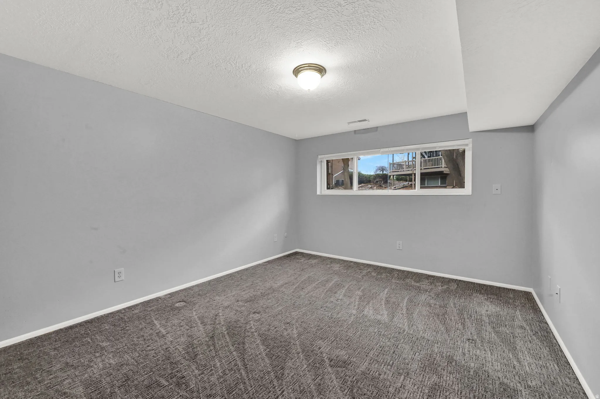 Empty room with carpet flooring and a textured ceiling