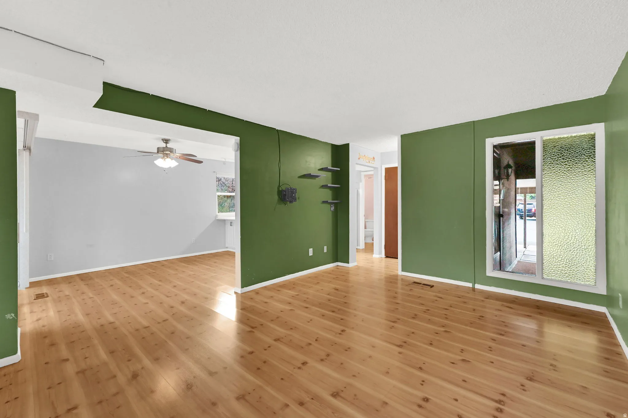 Empty room featuring healthy amount of natural light, hardwood / wood-style floors, and ceiling fan