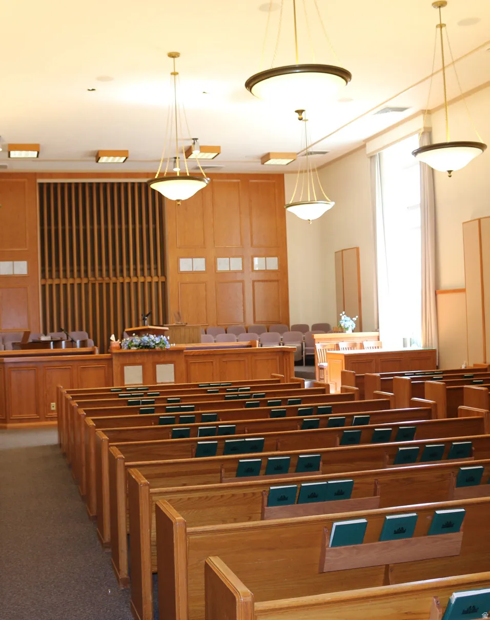 Interior chapel room with chandeliers, raised dais, and permanent benches