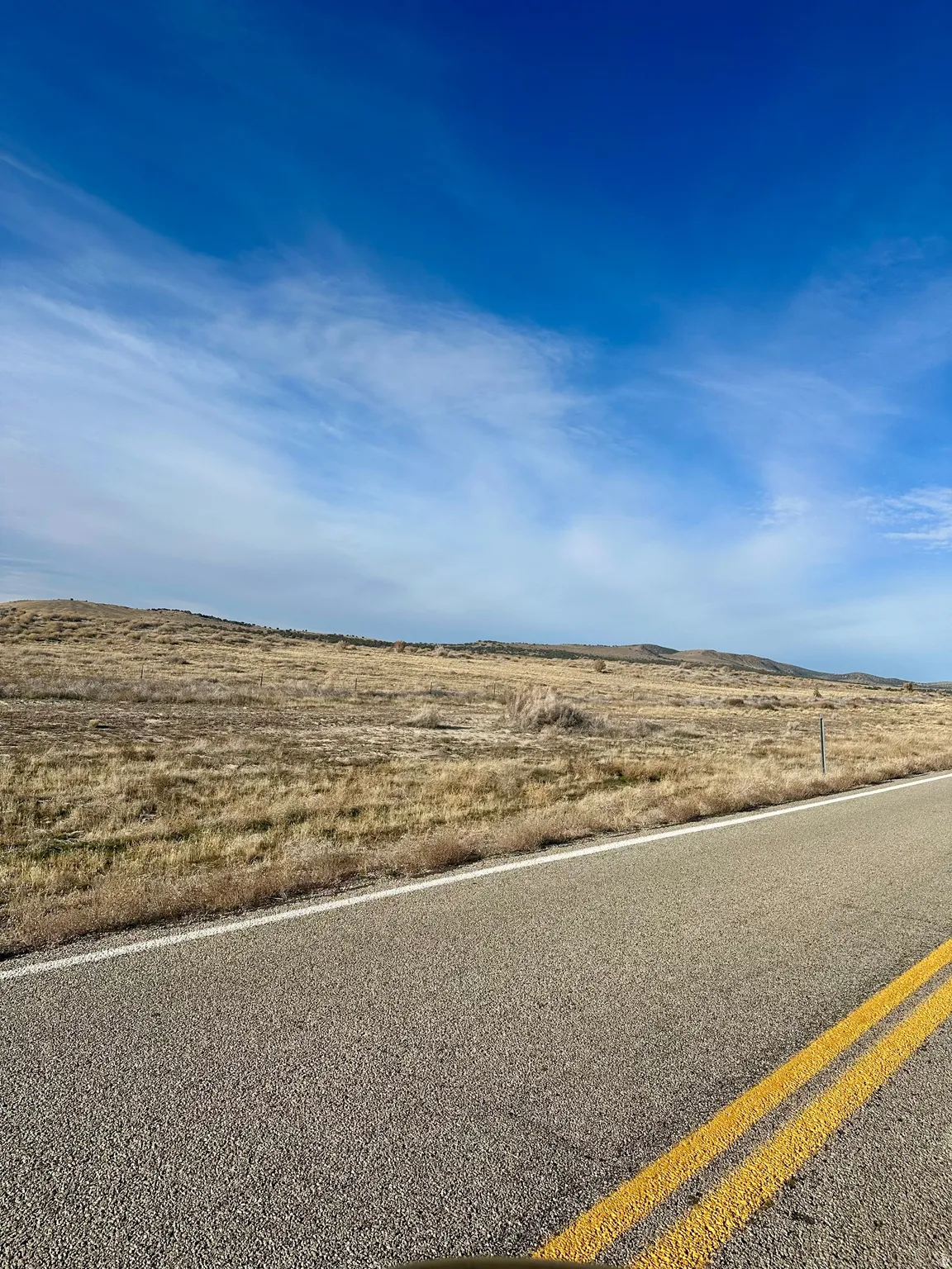 View of asphalt road with a view of rural / pastoral area