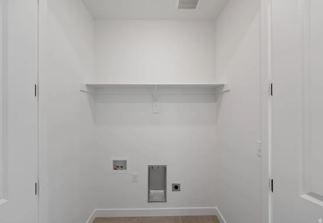 Laundry area with hookup for a washing machine, electric dryer hookup, and light tile patterned flooring