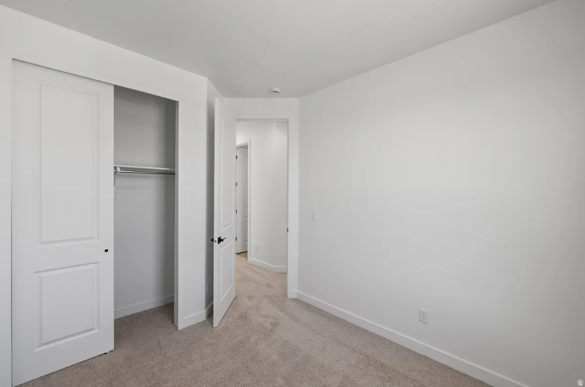 Unfurnished bedroom featuring light colored carpet and a closet