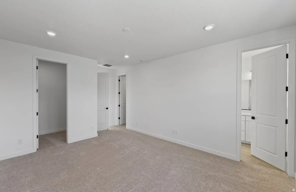 Unfurnished bedroom featuring light colored carpet, recessed lighting, and ensuite bathroom