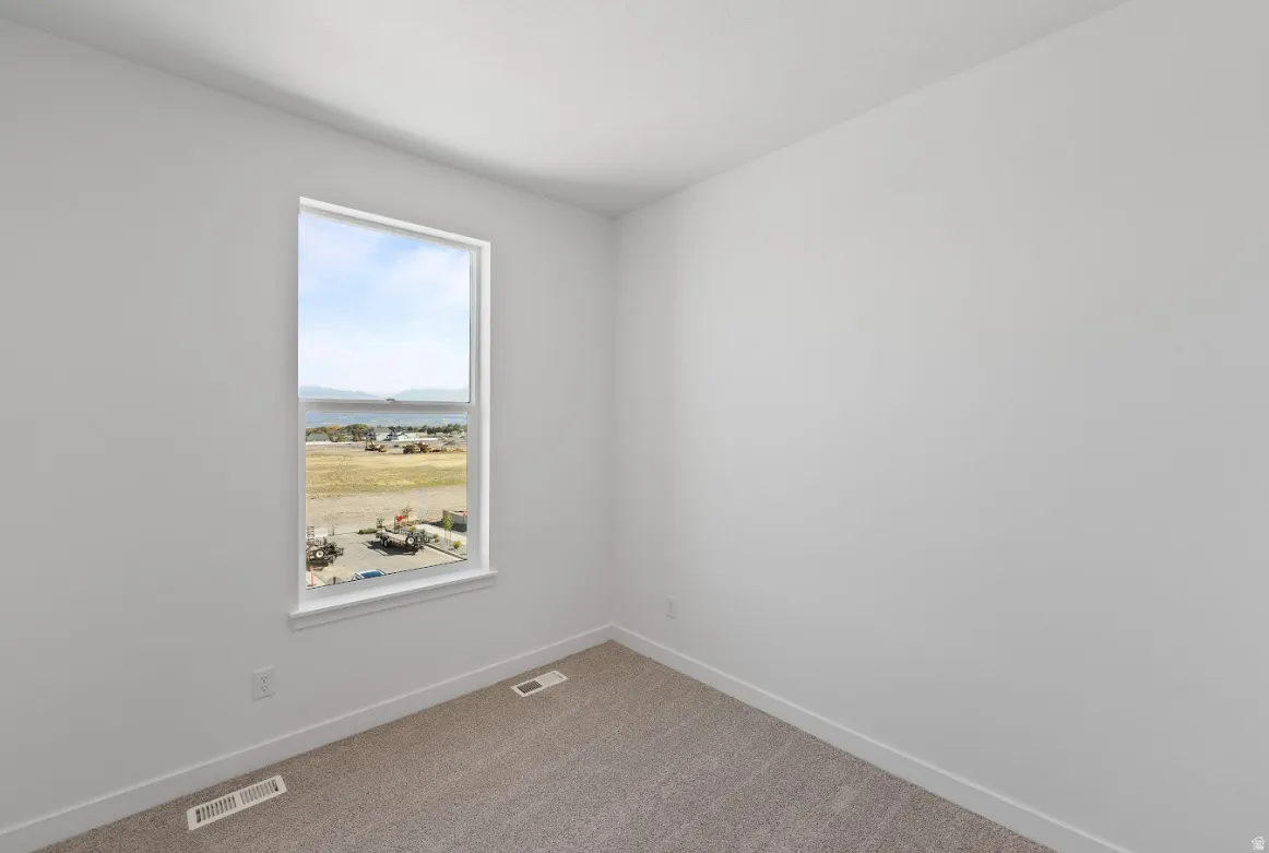 Carpeted empty room featuring baseboards and a water view