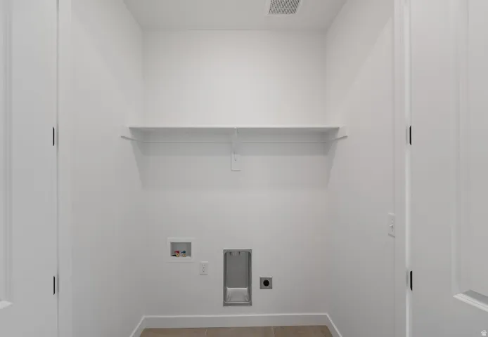 Laundry area with hookup for a washing machine, electric dryer hookup, and light tile patterned flooring