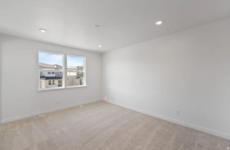Empty room with light colored carpet and recessed lighting