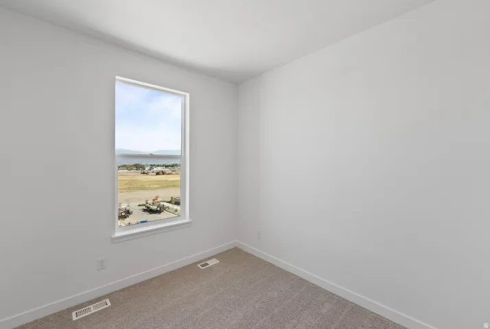 Carpeted empty room featuring baseboards and a water view