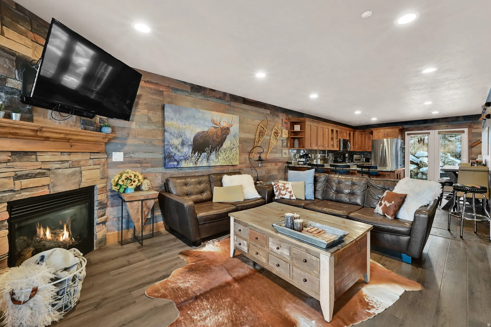 Living room featuring wood walls, recessed lighting, wood finished floors, and a stone fireplace