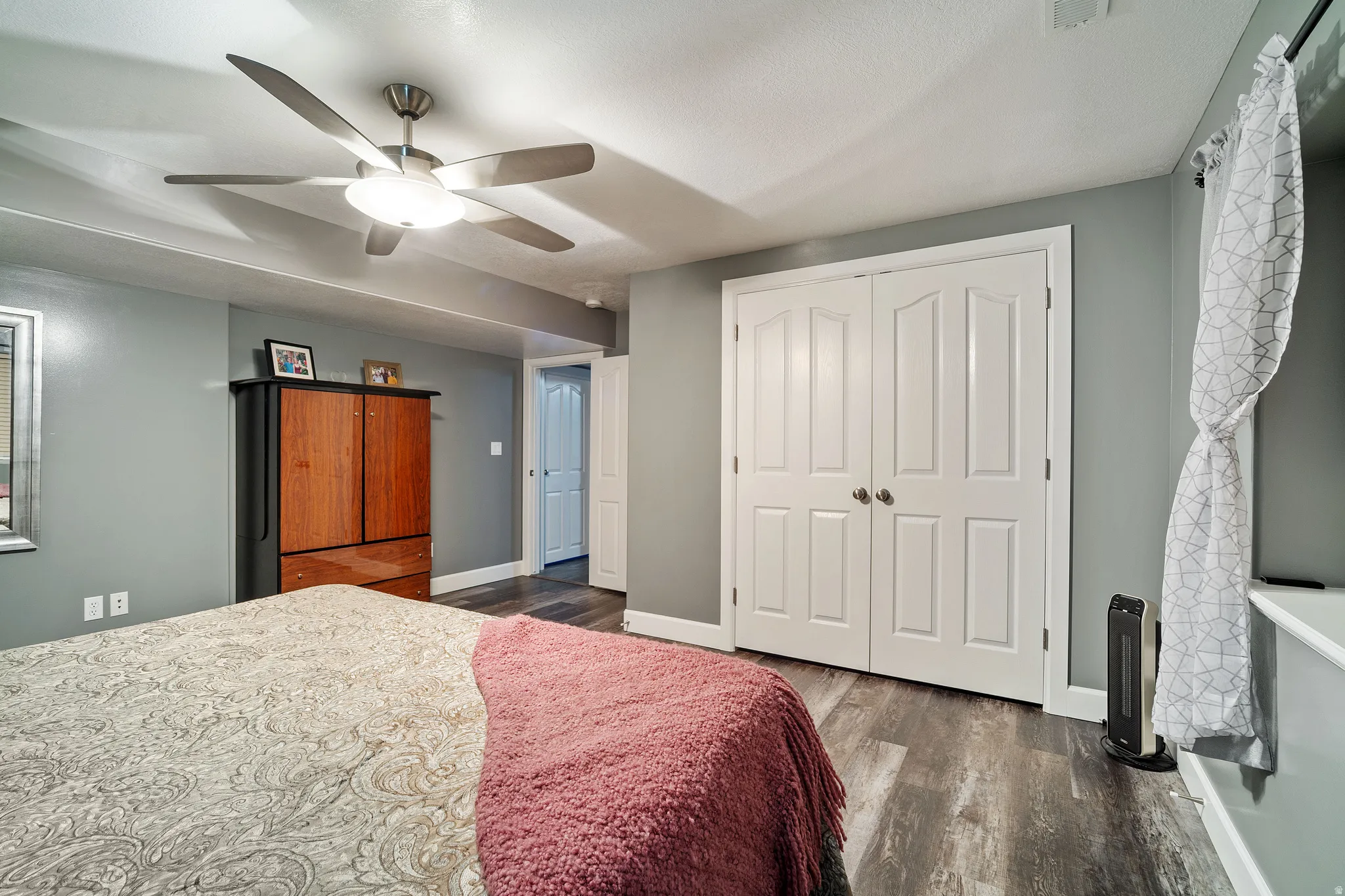 Bedroom with a closet, dark wood-style floors, and a ceiling fan