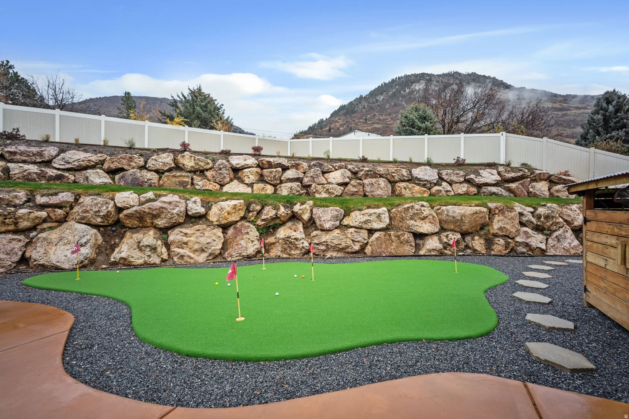 View of home's community with a putting green, a mountain view, and a fenced backyard