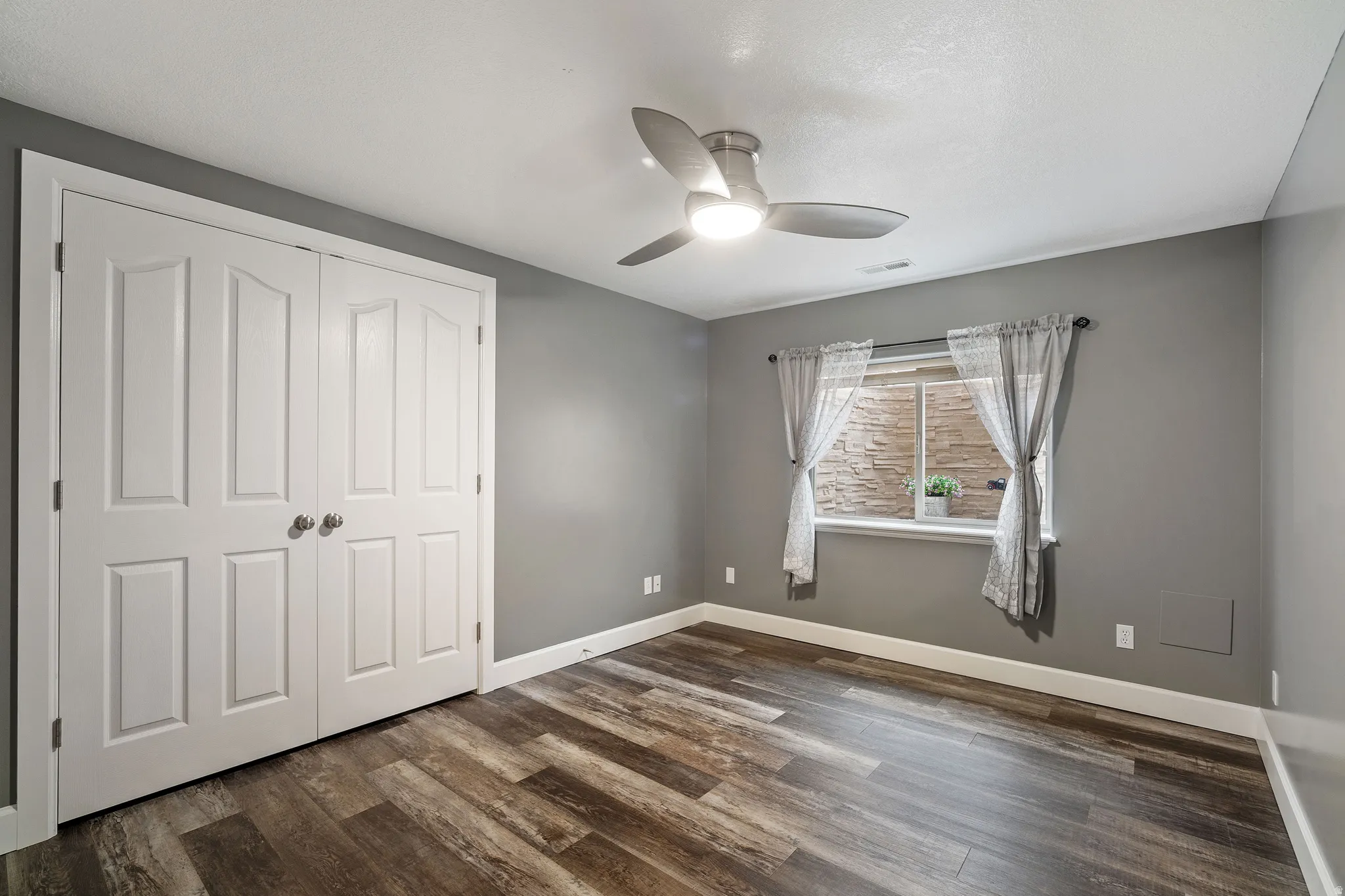 Unfurnished bedroom with a closet, ceiling fan, and dark wood-style flooring
