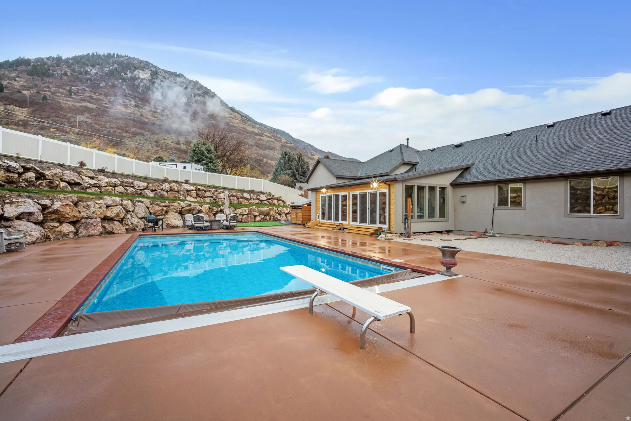View of swimming pool with a fenced backyard, a diving board, a patio area, a mountain view, and a sunroom
