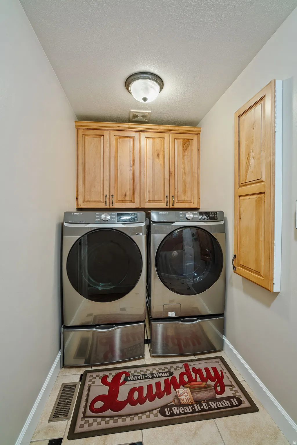 Washroom featuring cabinet space, separate washer and dryer, and a textured ceiling
