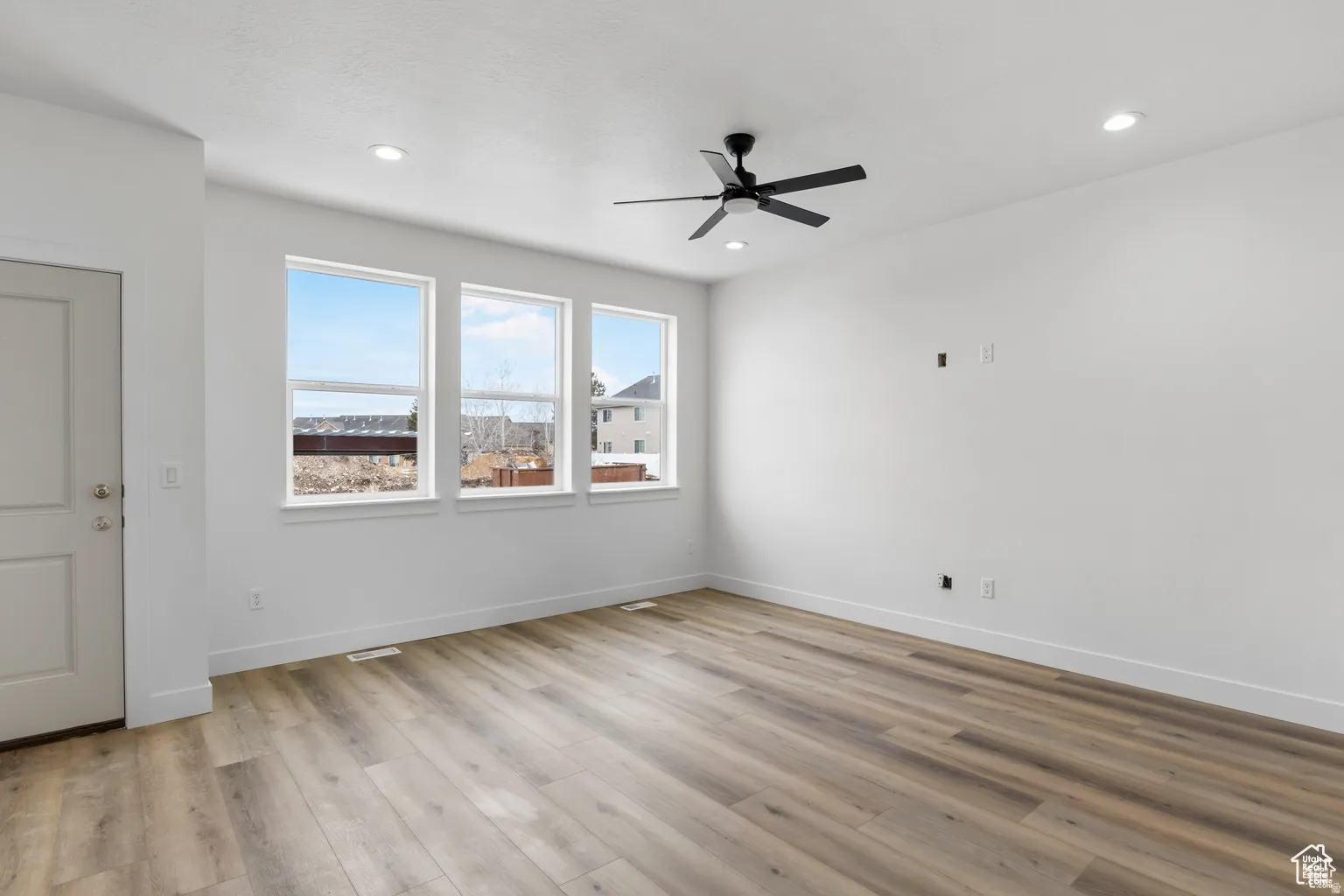 Empty room featuring light wood finished floors, ceiling fan, and recessed lighting