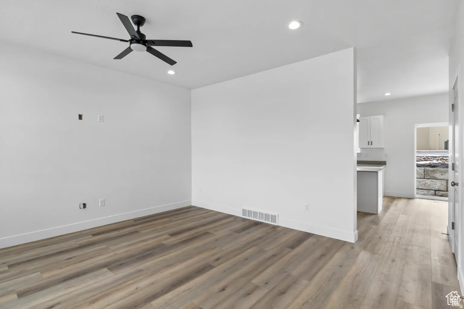 Empty room featuring light wood-type flooring, a ceiling fan, and recessed lighting