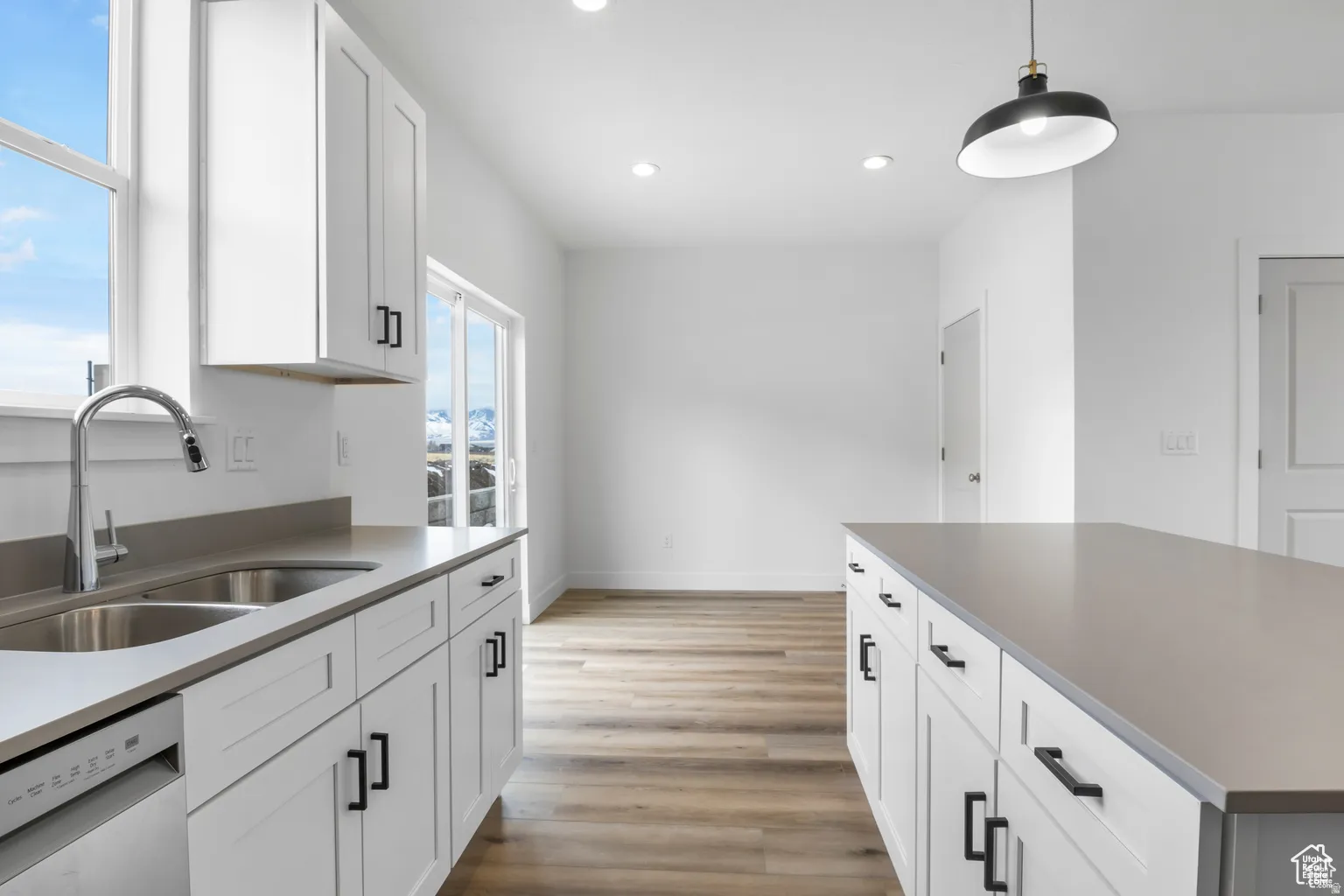 Kitchen with white cabinets, dishwasher, decorative light fixtures, light wood-type flooring, and recessed lighting