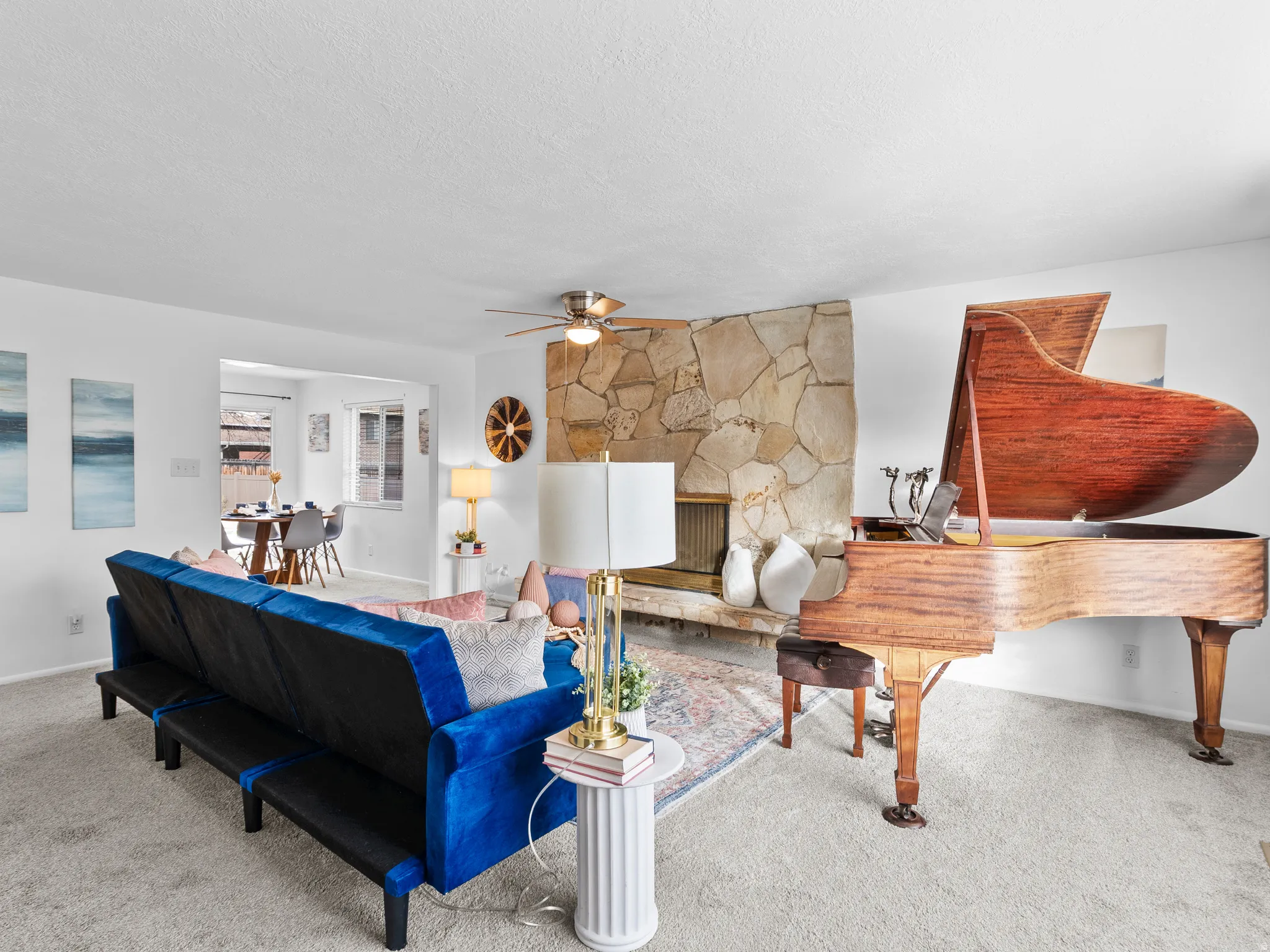 Carpeted living room with a fireplace, a textured ceiling, and ceiling fan