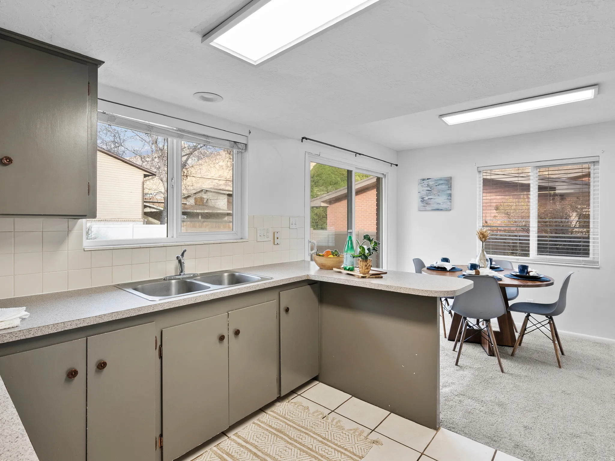 Kitchen with decorative backsplash, light countertops, a peninsula, light tile patterned floors, and plenty of natural light