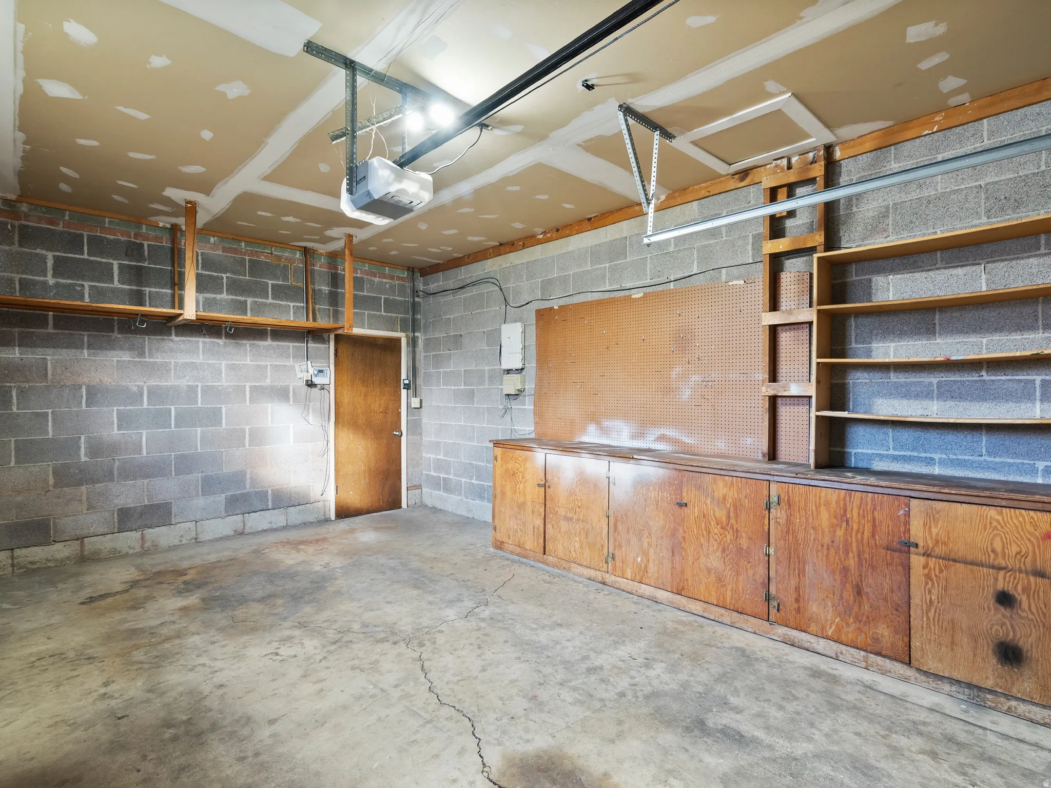 Garage featuring concrete block wall and a garage door opener
