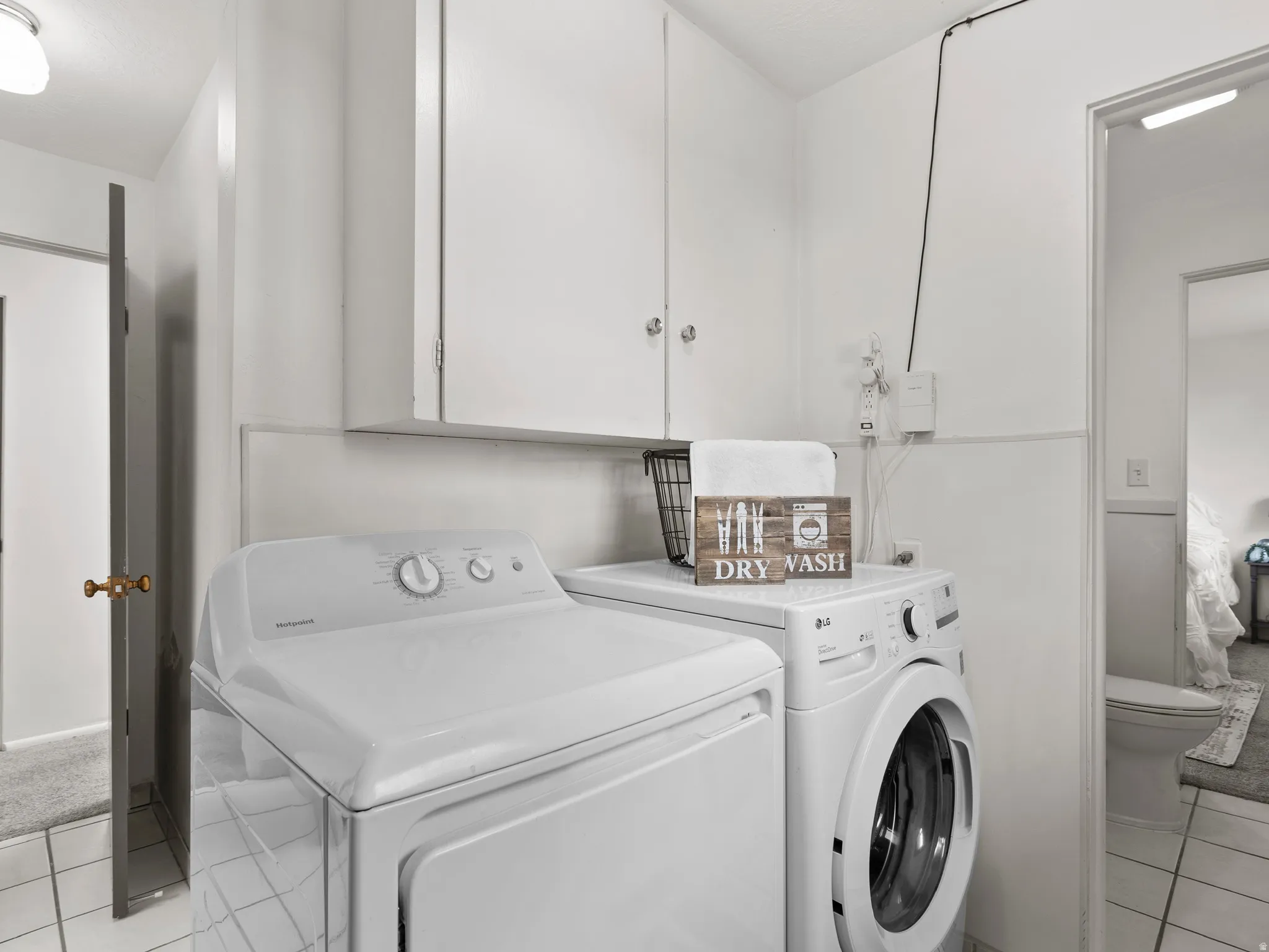Laundry room with light tile patterned flooring, washer and dryer, and cabinet space