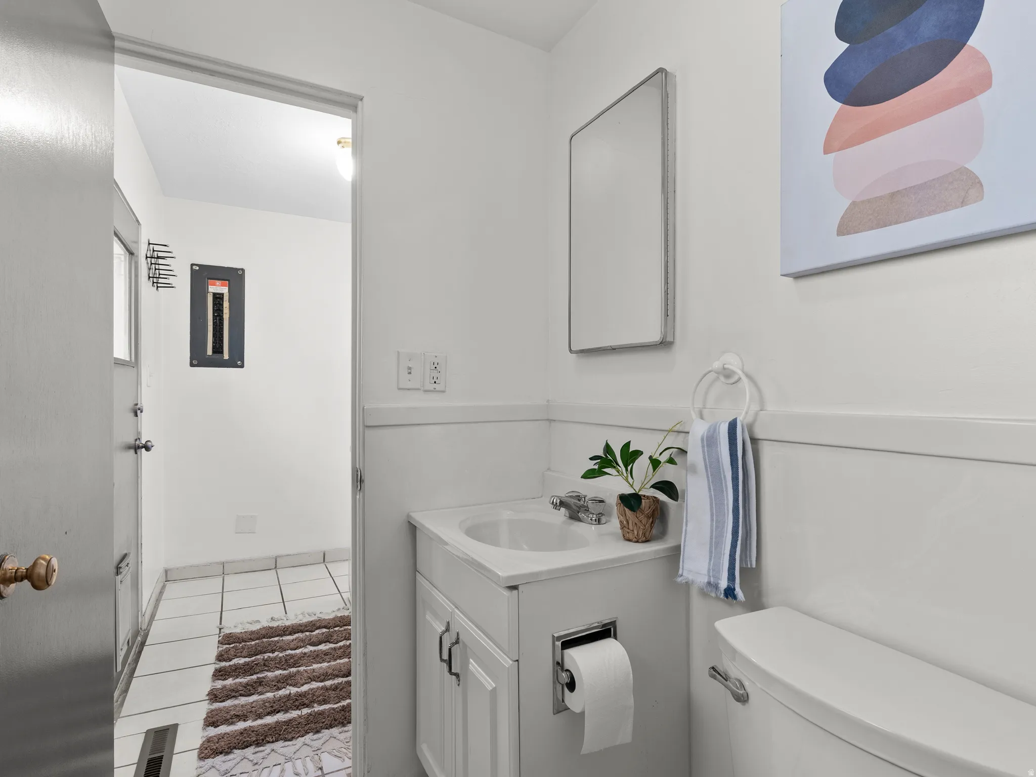 Half bathroom featuring vanity, electric panel, and light tile patterned floors