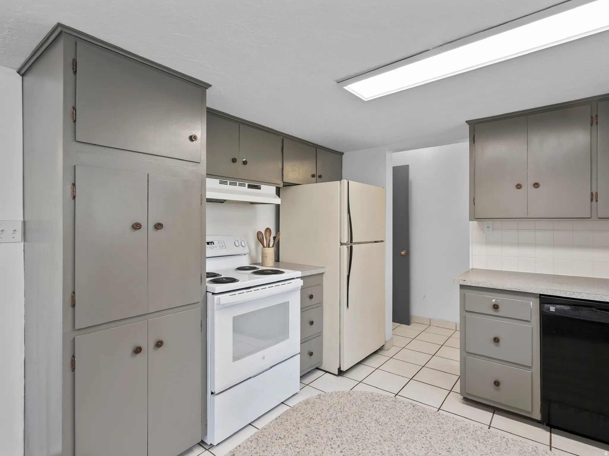Kitchen featuring gray cabinetry, white appliances, light countertops, and under cabinet range hood