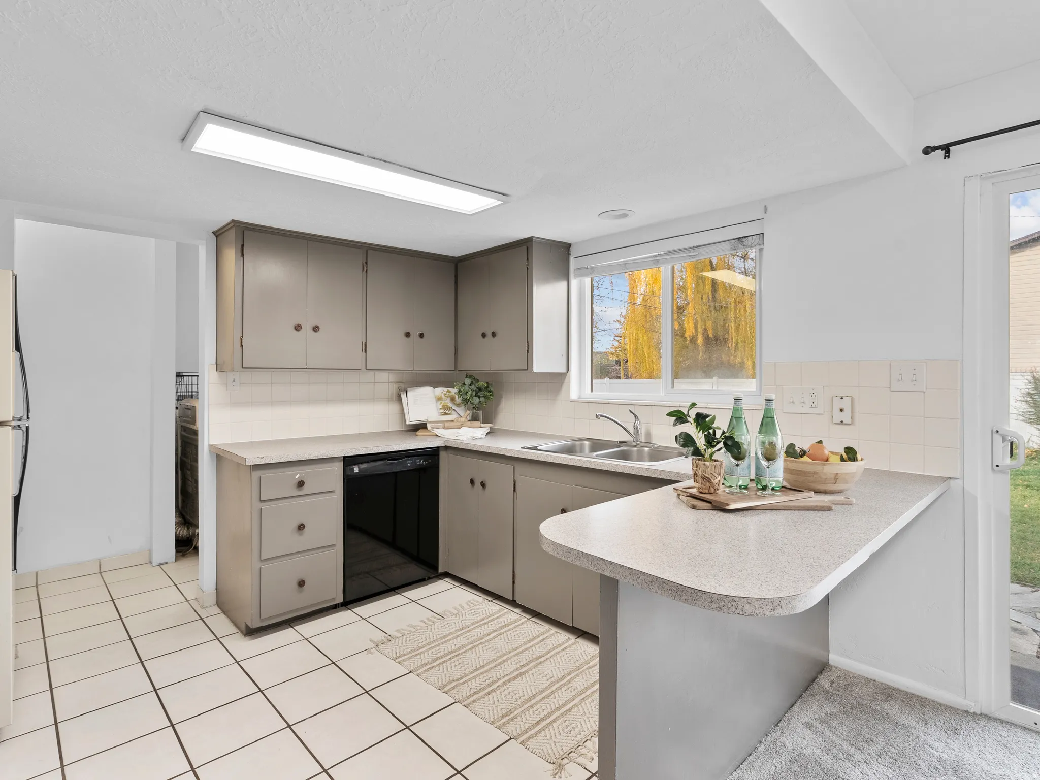 Kitchen featuring a peninsula, tasteful backsplash, black dishwasher, and light countertops