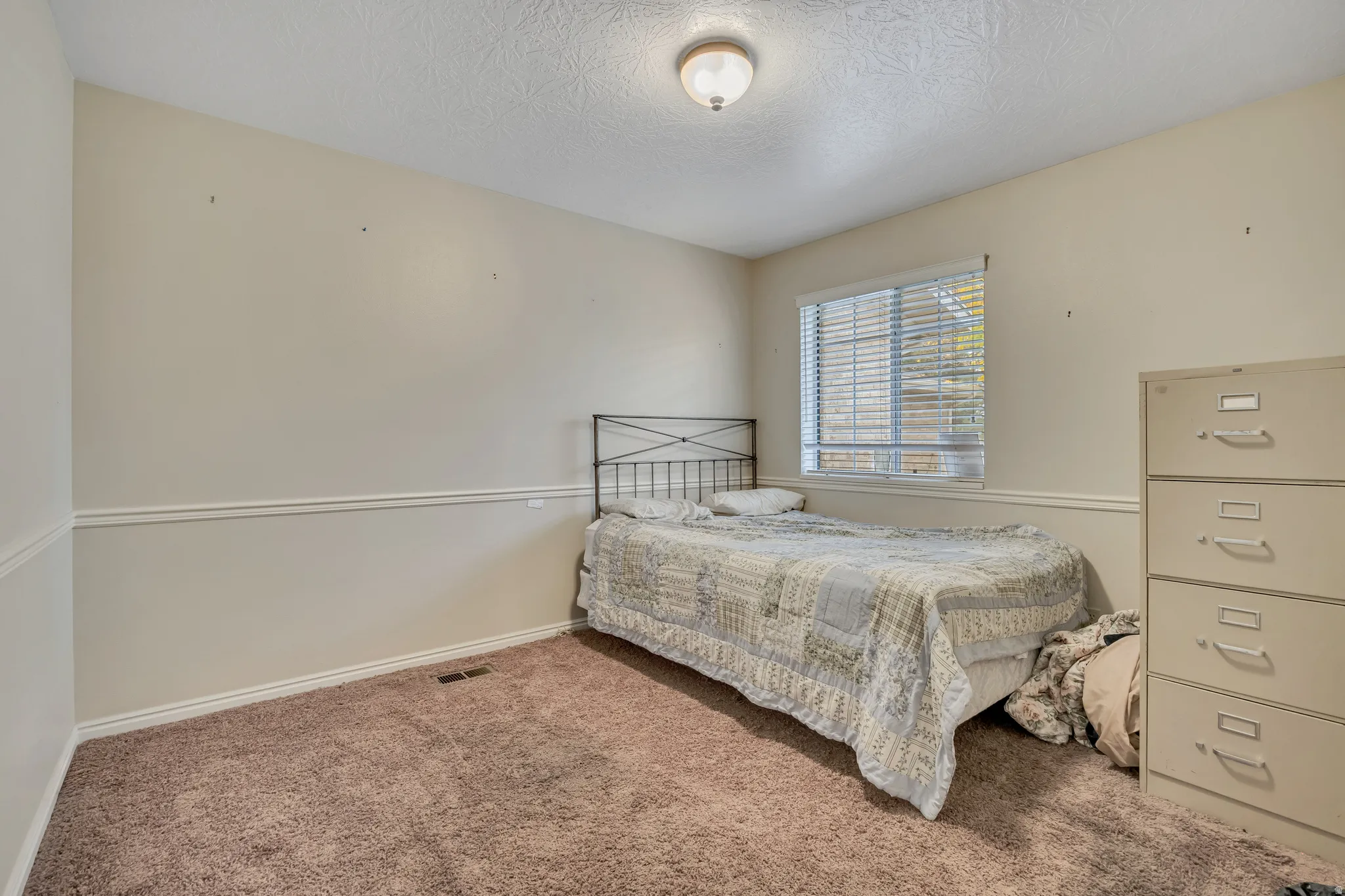 Bedroom with a textured ceiling and carpet floors