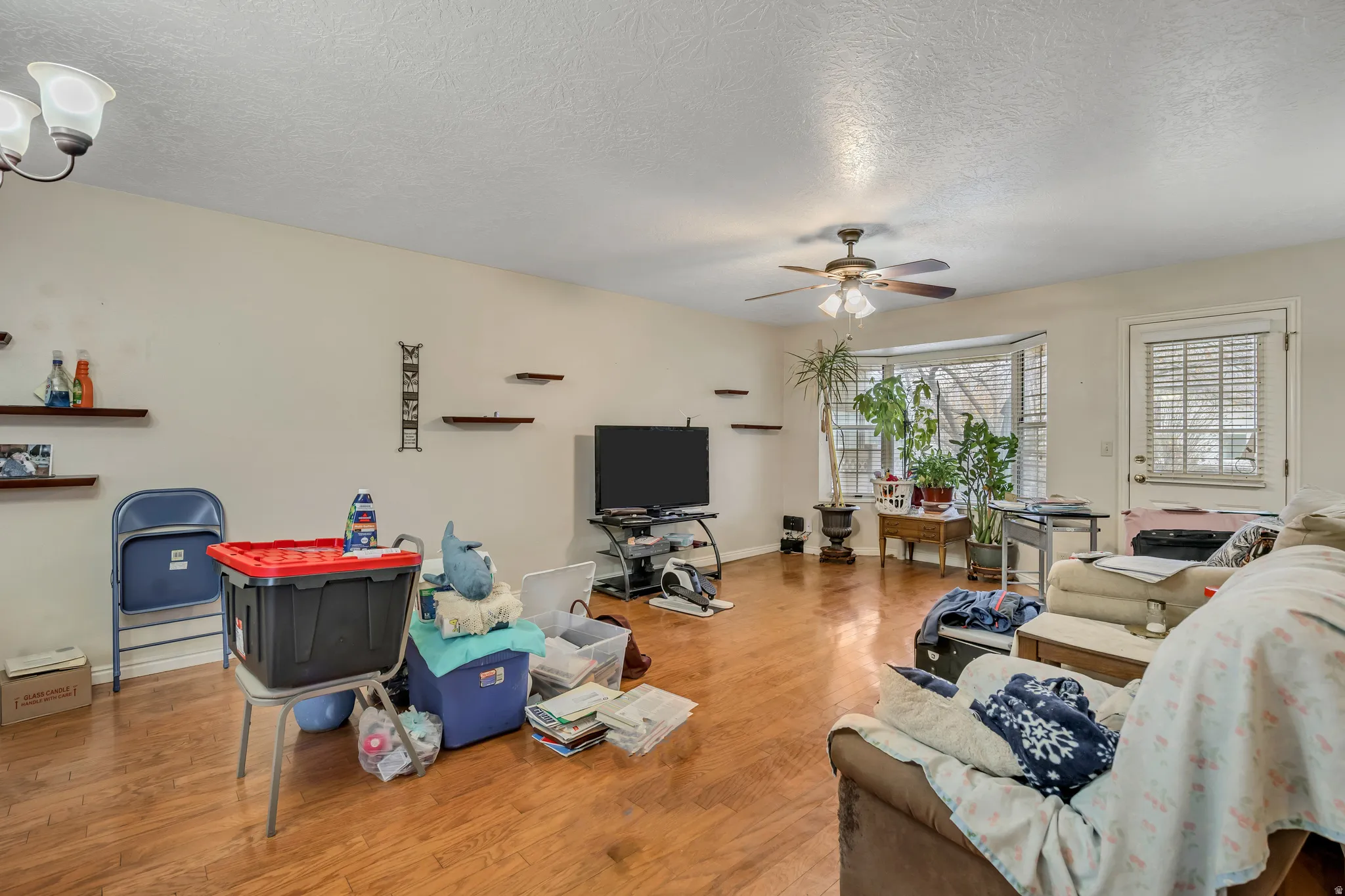 Living area with a textured ceiling, wood finished floors, and a ceiling fan