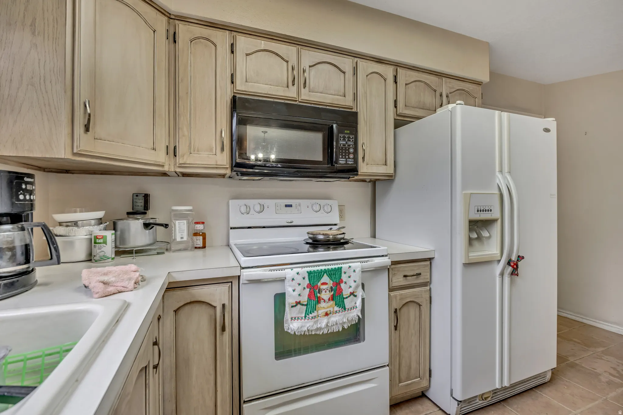 Kitchen with light brown cabinets, white appliances, and light countertops