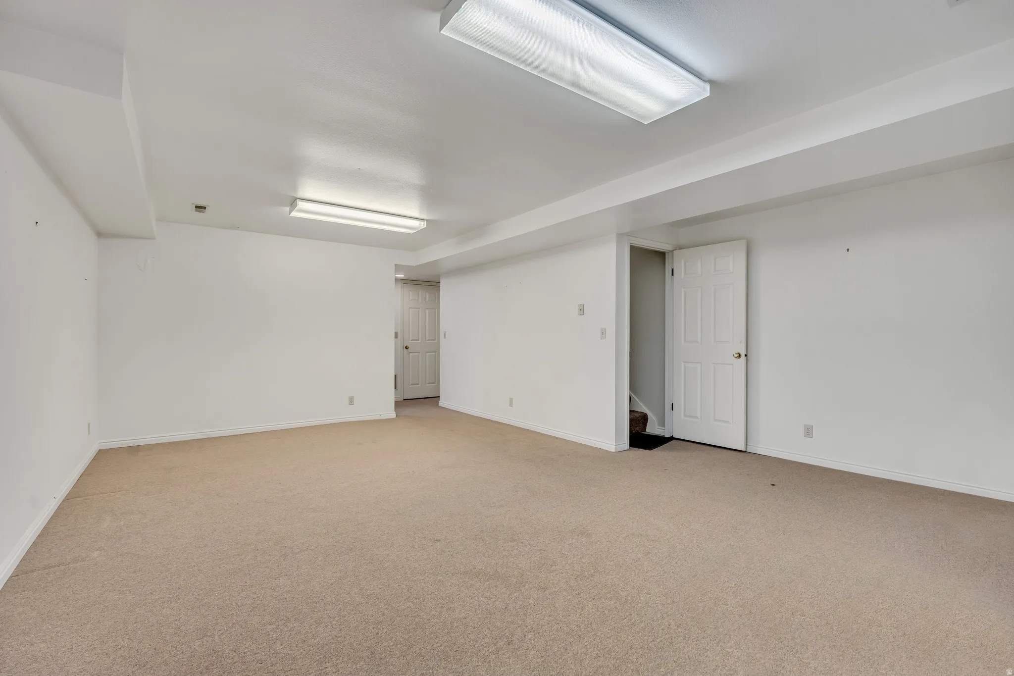 Unfurnished room with light colored carpet and stairs