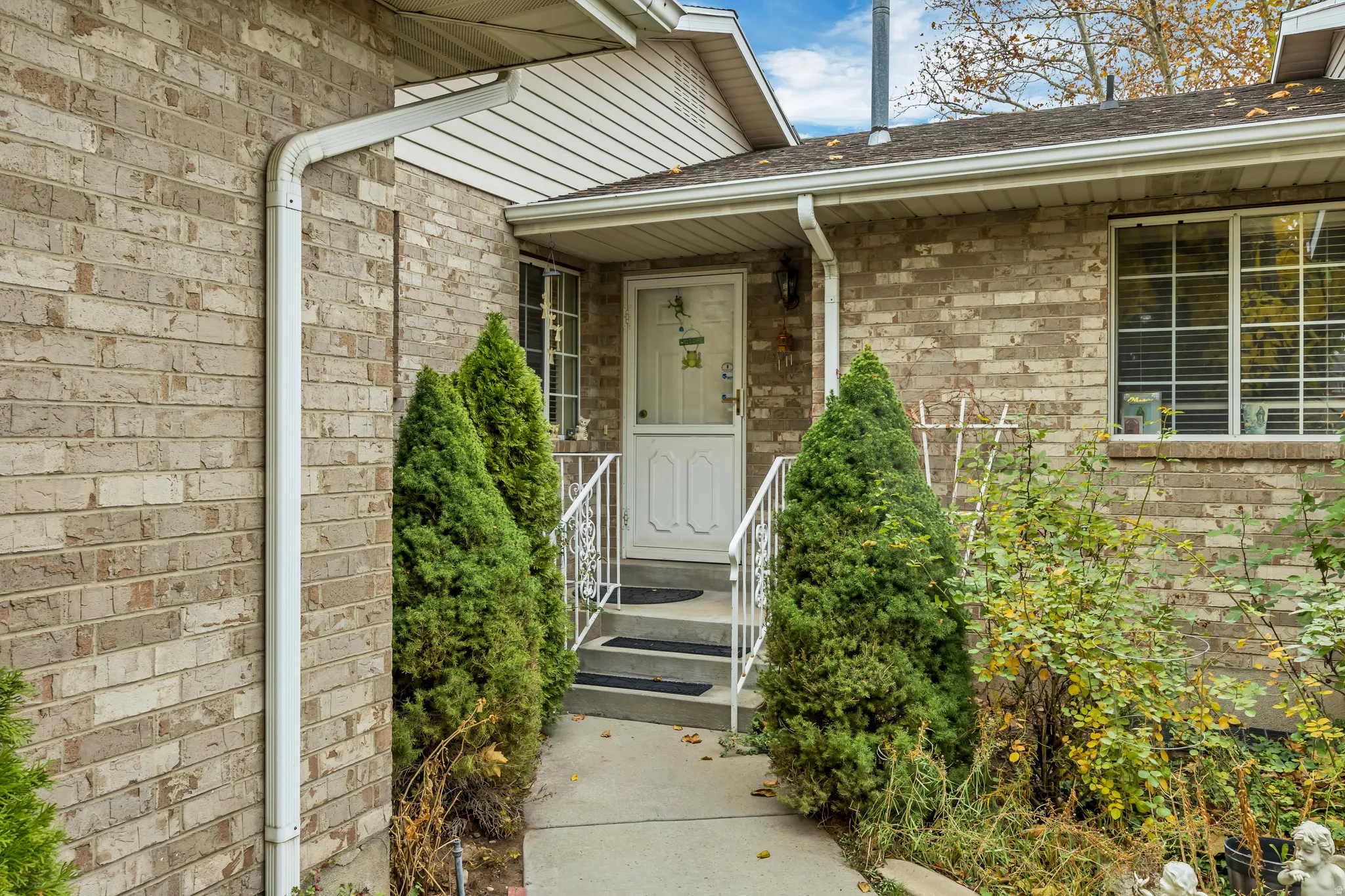 View of exterior entry with a shingled roof and brick siding