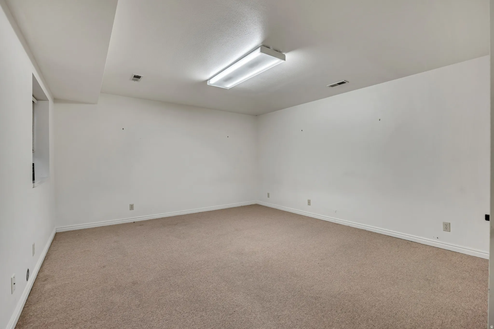 Spare room featuring light colored carpet and baseboards