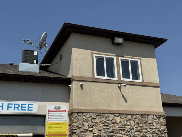 View of side of property featuring stone siding, stucco siding, and roof with shingles
