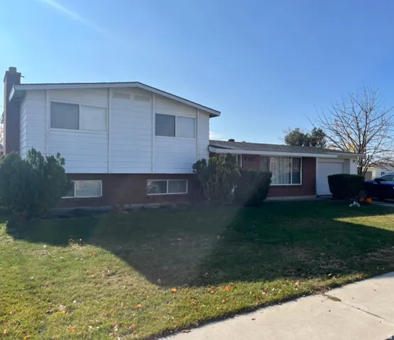 View of front facade with a front yard, a chimney, a garage, and brick siding