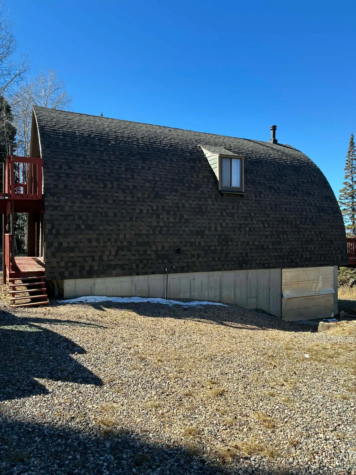 View of side of property with a deck and roof with shingles